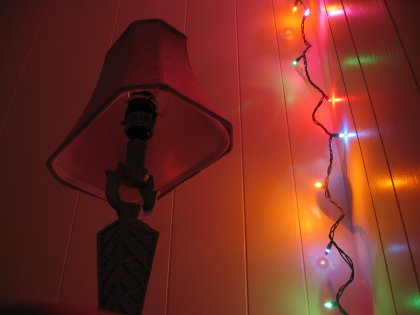 Christmas lights illuminating the wall behind my table lamp in a warm, inviting manner